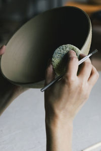 Female entrepreneur painting bowl with sponge in ceramics workshop