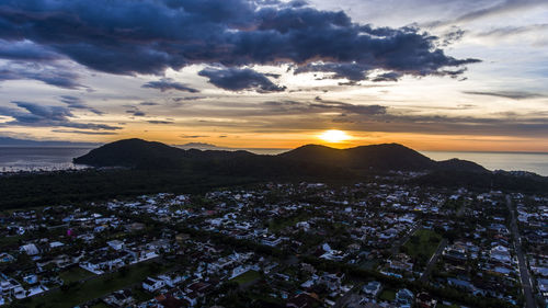 Aerial view of sea and cityscape against sky during sunset