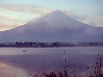 Boat with fisherman floating on lake kawaguchi on morning time with fuji mountain background