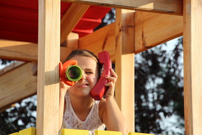 Girl talking on telephone while looking through telescope