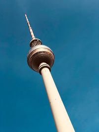 Low angle view of communications tower against blue sky