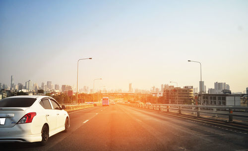 Traffic on road in city against clear sky