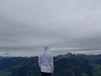 Rear view of man standing on mountain against sky