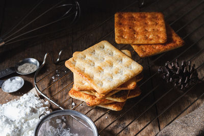 Square dry crackers biscuit on a wooden table. wooden texture dark background. snack dry biscuits