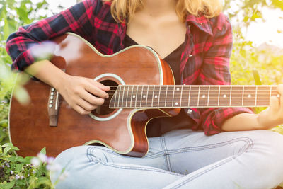 Midsection of woman playing guitar