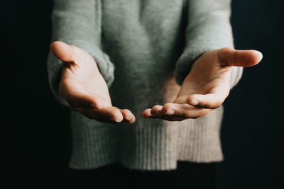 Cropped hand of woman gesturing against wall