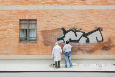 Rear view of children on brick wall