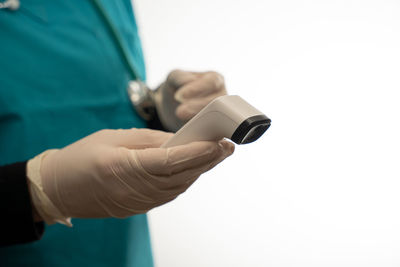 Midsection of doctor holding thermometer against white background