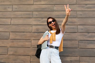 Young woman making peace sign against wall