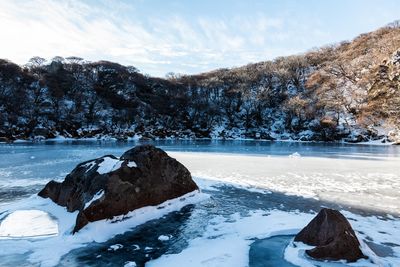 Frozen lake by snowcapped mountain against sky