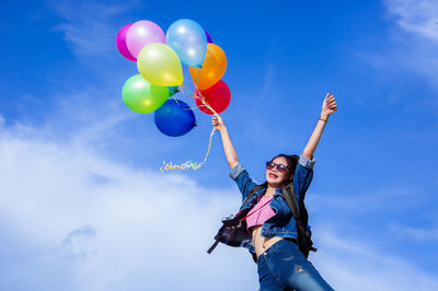 Low angle view of woman with balloons against sky