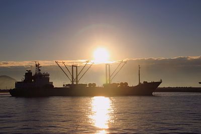 Silhouette of boat sailing in sea during sunset