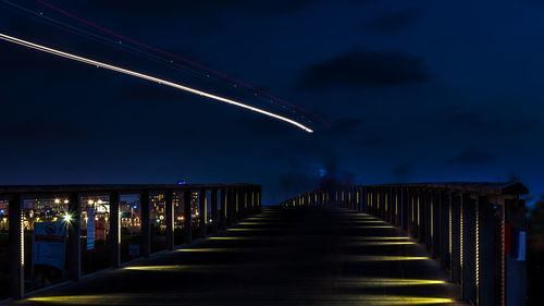 Illuminated footbridge against sky