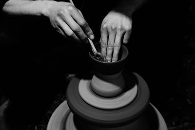 Cropped hands shaping pottery in darkroom