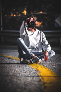 Full length of man photographing while sitting on road