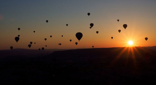 Silhouette of hot air balloons against sky during sunset