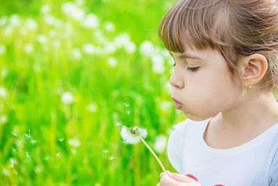 Close-up of girl blowing dandelion