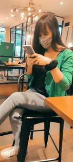 Young man using mobile phone while sitting on chair