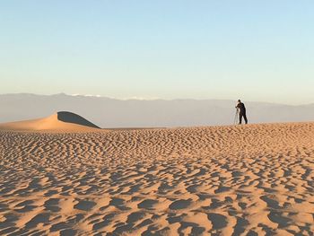 Man standing on sand dune against clear sky