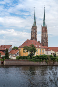 Buildings by river against sky