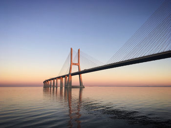 Bridge over sea against sky during sunset