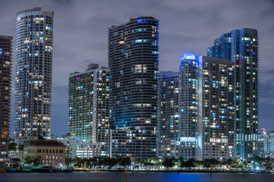 Illuminated buildings in city against sky at night