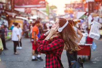 Smiling beautiful woman wearing headphones on street in city