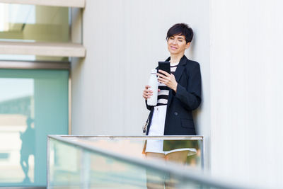 Portrait of businessman standing against wall