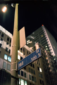 Low angle view of road sign against building at night