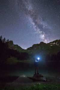 Man holding illuminated flashlight against star field