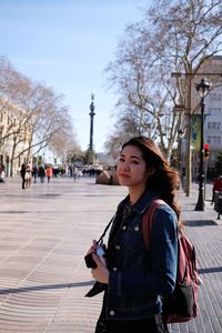 Woman standing on footpath in city