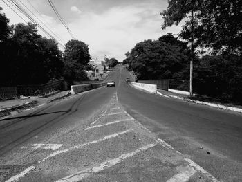 Road by trees against sky