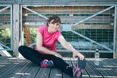 Full length of woman sitting on pink floor