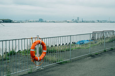 Orange railing by sea against sky