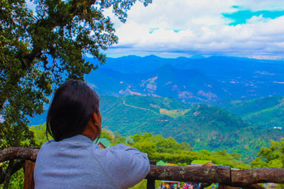 Side view of woman looking at mountains against sky