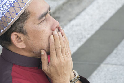 Close-up of mature man praying while sitting at mosque