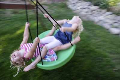 High angle view of happy sisters swinging at playground