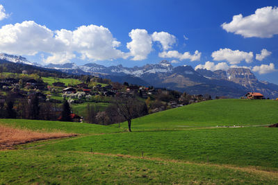 Scenic view of green landscape and mountains against sky