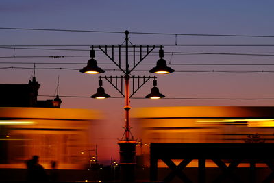 Illuminated street light against sky at sunset