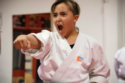 Teenage girl practicing karate in room