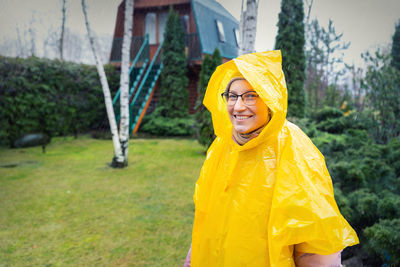 Portrait of smiling young woman standing in rain