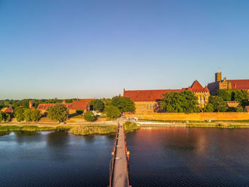 Scenic view of river by buildings against clear blue sky