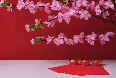 Close-up of red flowers in vase on table against wall