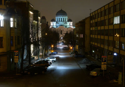 Illuminated street amidst buildings in city at night