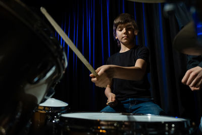 Cute boy playing drum at concert