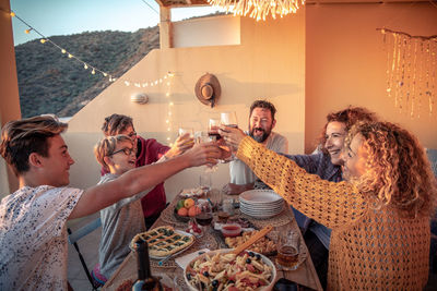 Friends toasting drinks at table during sunset