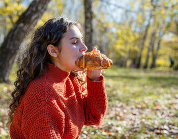 Leisure, free time. beautiful caucasian woman in red sweater on a picnic outdoors, sitting on a pla