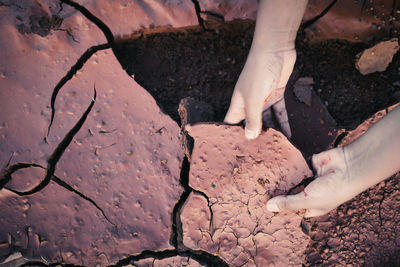 Cropped image of hands removing cracked cement over mud