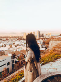 Rear view of woman looking at city buildings against sky