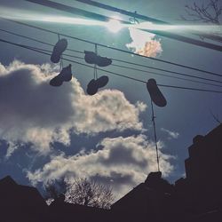 Low angle view of power lines against cloudy sky